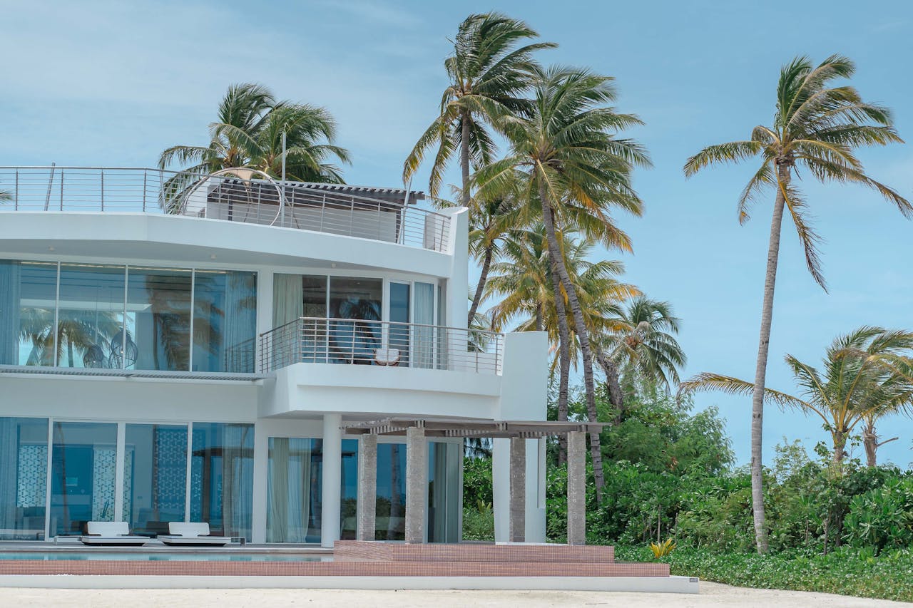 Beautiful beachfront villa with palm trees and ocean view, ideal for vacation and relaxation.
