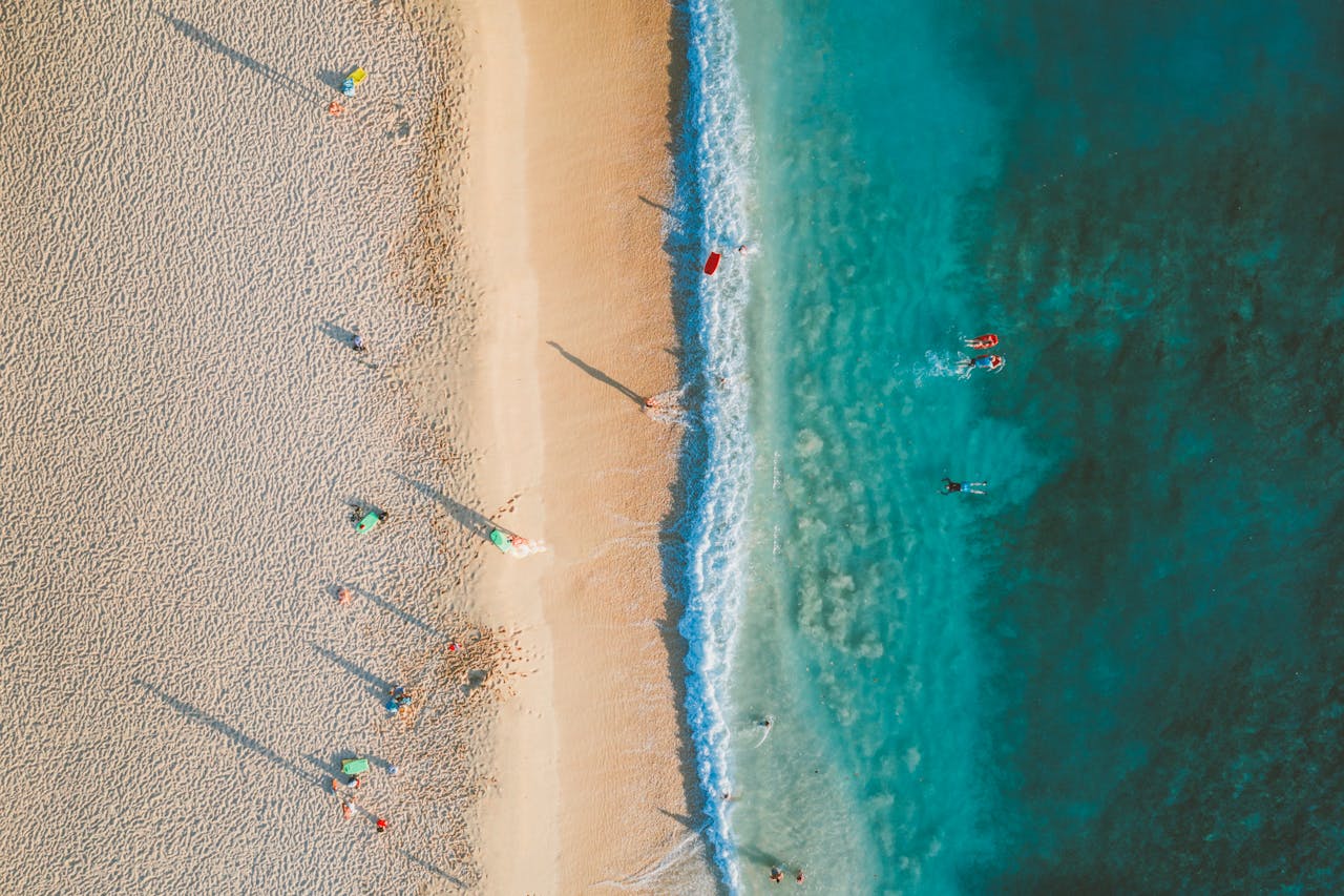 Breathtaking aerial view of a Hawaiian beach with beachgoers and turquoise waters.